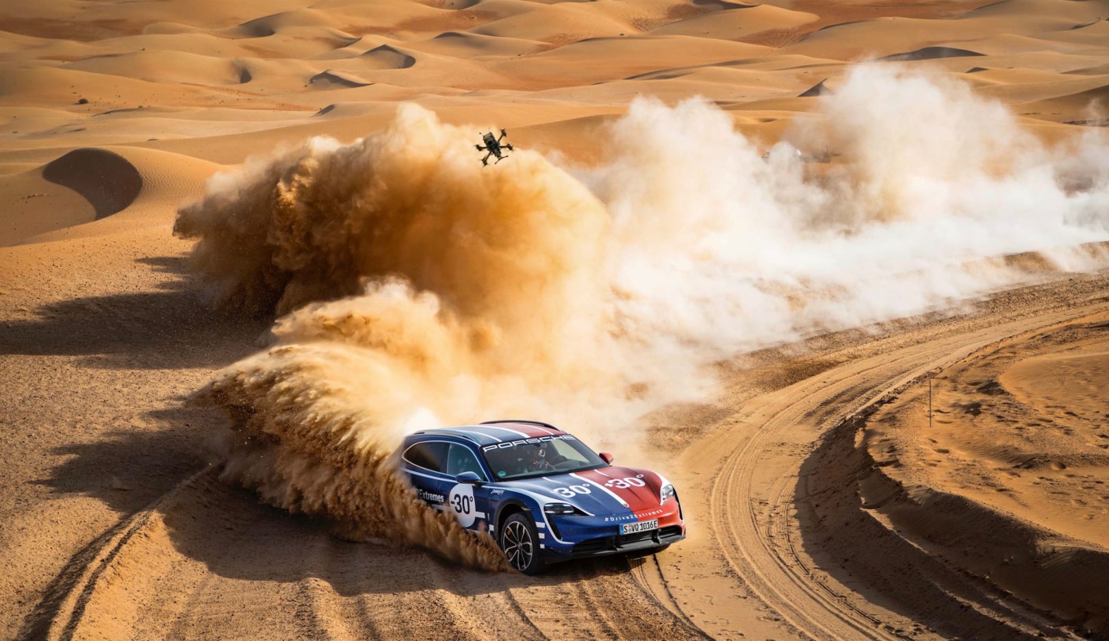 Porsche Taycan Cross Turismo rally car in desert action shot with drone overhead
